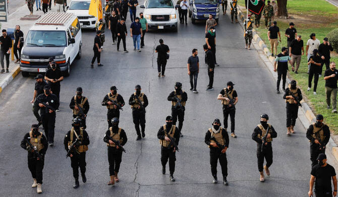 A vehicle carries the coffin of a commander from Iraq's Kataib Hezbollah armed group who was killed in what they called a 