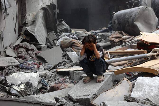 A Palestinian boy squats on the rubble of a building at the site of an Israeli strike on a residential area in Gaza City's Shujaiyya neighbourhood, on April 9, 2025. (AFP)