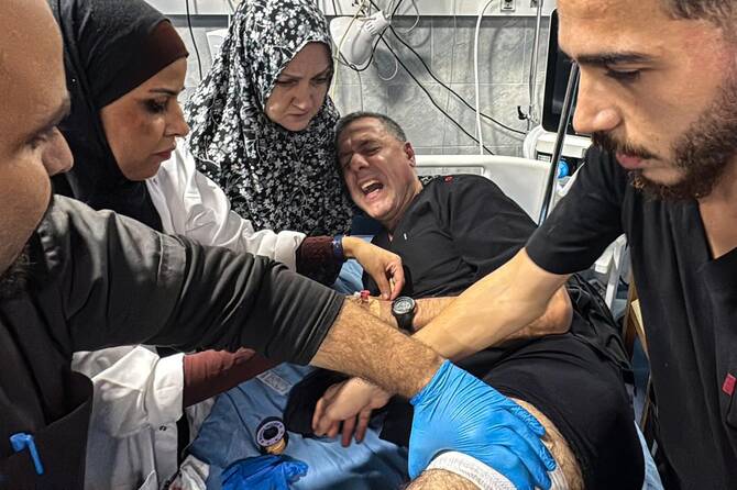 Hussam Abu Safiya, the director of the Kamal Adwan Hospital, is treated by colleagues for his injuries following an Israeli strike that according to the civil defence in Gaza hit the medical compound in Beit Lahia in the northern Gaza Strip, late on November 23, 2024. (AFP)