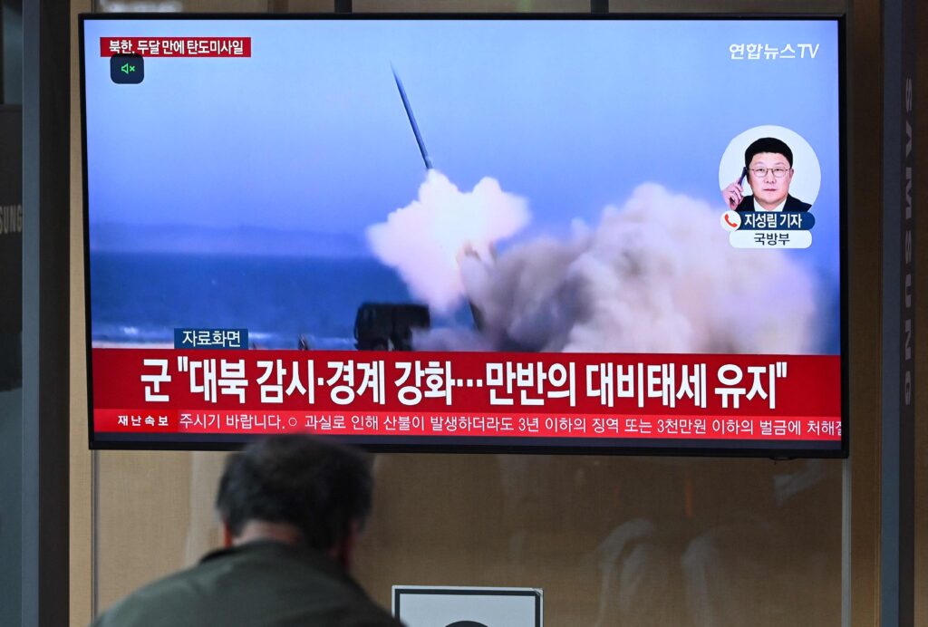 A man watches a television screen showing a news broadcast with file footage of a North Korean missile test, at a train station in Seoul on May 8, 2025. (AFP)