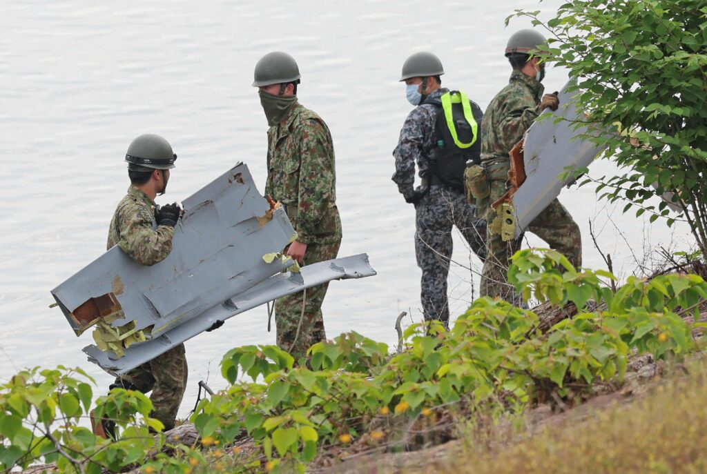 Members of the Japan Self-Defense Forces carry debris believed to be part of the aircraft recovered by boat from Lake Iruka, where a Japan Air Self-Defense Force training plane T-4 crashed, in Inuyama City, Aichi Prefecture on May 15, 2025. (AFP)
