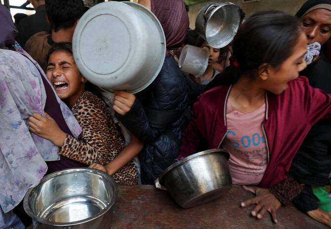 Palestinians wait to receive food cooked by a charity kitchen, in Gaza City, May 21, 2025. REUTERS/Mahmoud Issa