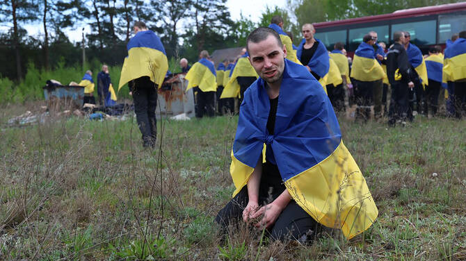 205 Ukrainian prisoners of war wrapped with national flags, following an exchange at an undisclosed location, May 6, 2025. (AFP)