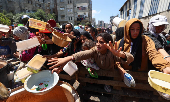 Displaced Palestinians scuffle for a portion of hot food at a charity kitchen at the Nuseirat refugee camp in the central Gaza Strip on May 5, 2025. (AFP)