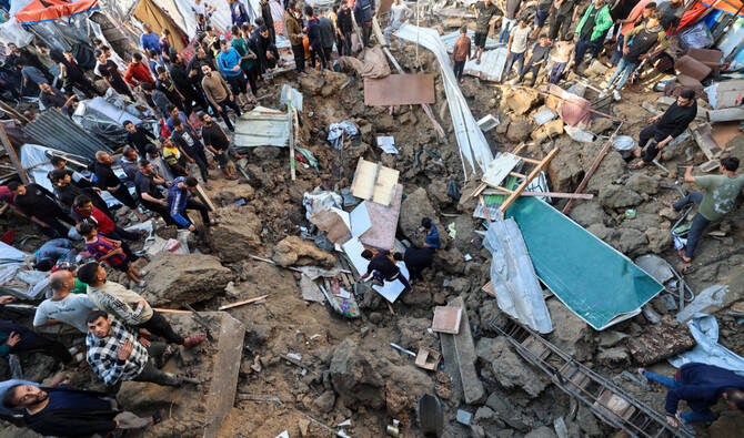 People search for survivors in a crater at the site of an Israeli strike at a UNWRA school housing displaced Palestinians at the Bureij camp for refugees in the central Gaza Strip on May 6, 2025. (AFP)