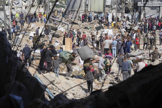 Palestinians collect belongings from a school in Gaza used as a shelter by displaced residents that was hit twice by Israeli army strikes on Tuesday, killing more than 25 people. (AP)