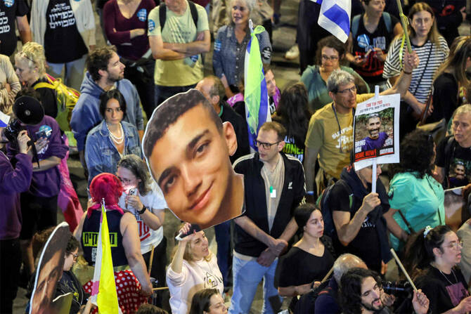 A demonstrator holds a sign showing the face of US-Israeli hostage Edan Alexander (C) during a protest outside the Israeli Defense Ministry headquarters in Tel Aviv on March 15, 2025. (AFP)