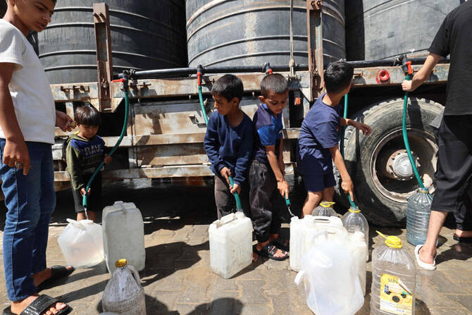 Palestinian boys fill their containers with water in the Nuseirat camp for refugees in the central Gaza Strip on May 24, 2025. (AFP)