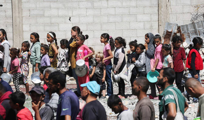 Palestinians gather to receive a hot meal at a food distribution point in the Nuseirat camp for refugees in the central Gaza Strip. (AFP)
