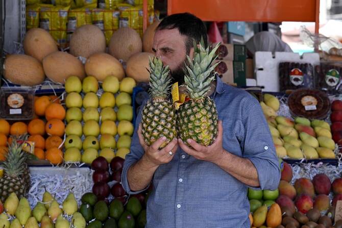A man holds two pineapples at a stall that sells fruits, some of which were not available while deposed president Bashar al-Assad was in power, like kiwi, mango and pineapple, in the Shalaan Market in the Syrian capital Damascus on May 26, 2025. (AFP)