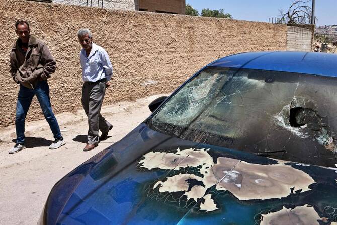 Palestinian men walk past a burned car reportedly set on fire during an attack by Israeli settlers in Rammun village, northeast of Ramallah in the occupied West Bank, on May 28, 2025. (AFP)