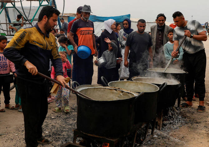 Palestinians gather to receive food cooked by a charity kitchen, in Khan Younis, southern Gaza Strip, Apr. 8, 2025. (Reuters)