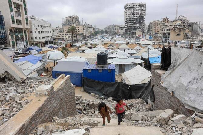 Girls play on the rubble of a Palestinian Authority’s Legislative Council building near a makeshift displacement camp set up amid building rubble in Gaza City on May 12, 2025. (AFP)