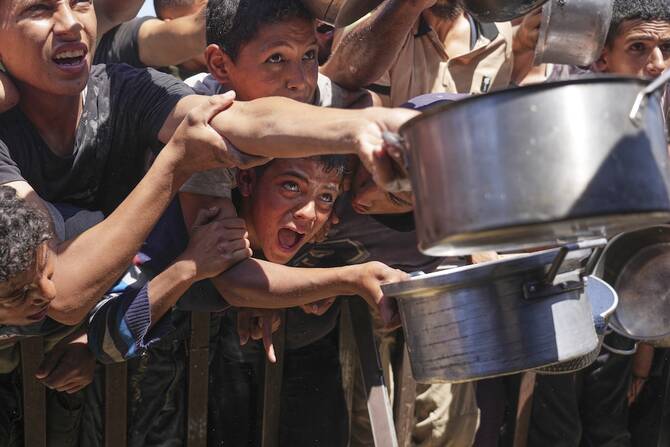 Palestinians struggle to receive food at a community kitchen in Khan Younis. (AP)