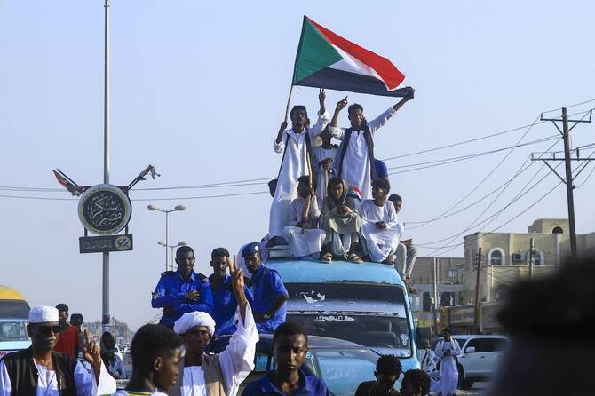 People lift national flags during a rally called for by Sudan's Popular Front for Liberation and Justice in Port Sudan. (File/AFP)