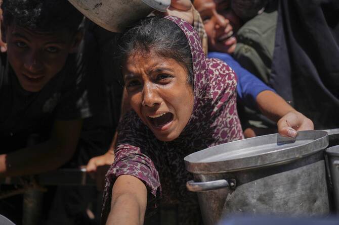Palestinians struggle to receive cooked food distributed at a community kitchen in the Muwasi area of Khan Younis, in the Gaza Strip on Friday. (AP)