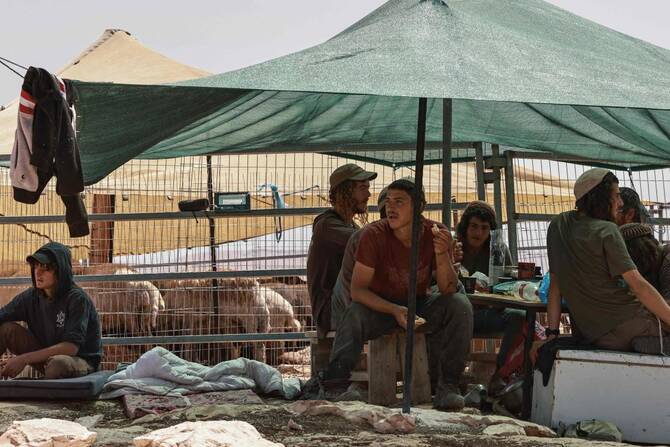 Israeli settlers sit in a tent in Al-Mughayyir village, north of Ramallah in the occupied West Bank, as Bedouin inhabitants nearby dismantle their living structures to evacuate from their village fearing settler attacks, on May 22, 2025. (AFP)