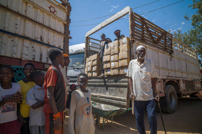 Children stand near trucks loaded with World Food Program (WFP) food assistance, in Omdurman, Sudan on April 17. (Reuters)