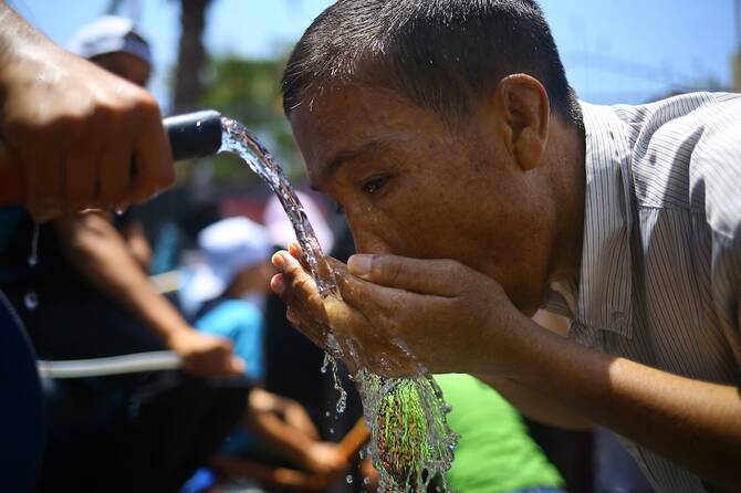 A Palestinian man drinks water to cool off during a demonstration against the siege of Gaza and in solidarity with Al-Aqsa Mosque, in Gaza City. (File/AFP)
