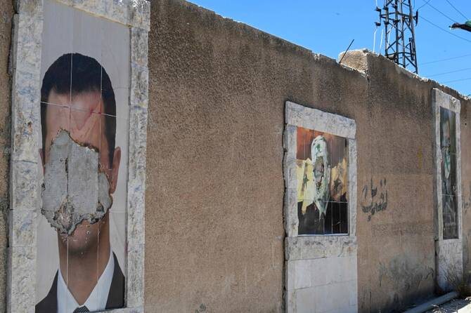 Defaced posters of Hafez and Bashar Al Assad on a wall in Damascus, Syria. (AP)