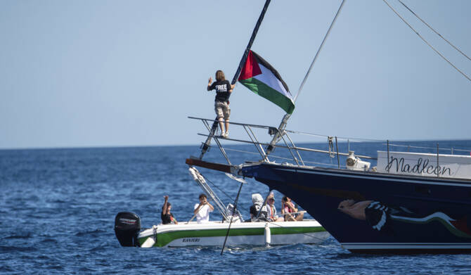 Climate activist Greta Thunberg stands near a Palestinian flag after boarding the Madleen boat and before setting sail for Gaza along with activists of the Freedom Flotilla Coalition, departing from the Sicilian port of Catania, Italy, Sunday, June 1, 2025. (AP)