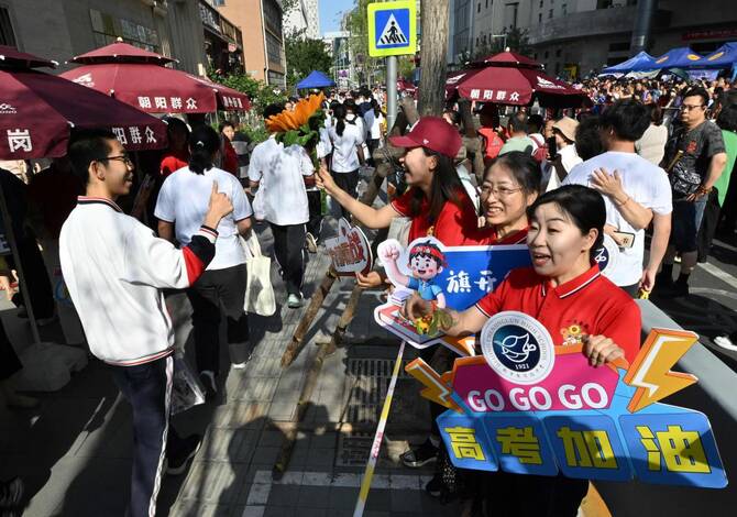 School staff members welcome students as they enter a school during China’s National College Entrance Examination, known as “gaokao”, outside a high school in Beijing on June 7, 2025. (AFP)