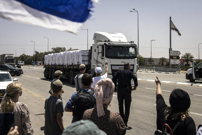Right-wing protesters gesture at a truck driving past during a protest to block humanitarian aid from entering Gaza at the Kerem Shalom crossing on May 21, 2025. (AFP/File)