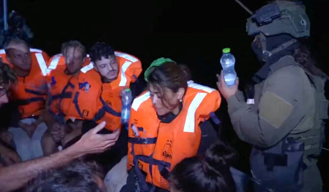 An Israeli solider passes water to those onboard the Gaza-bound British-flagged yacht