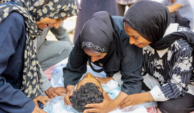 Women mourn over the body of a man killed during overnight Israeli bombardment on June 12, 2025, at al-Shifa hospital in Gaza City. (AFP)