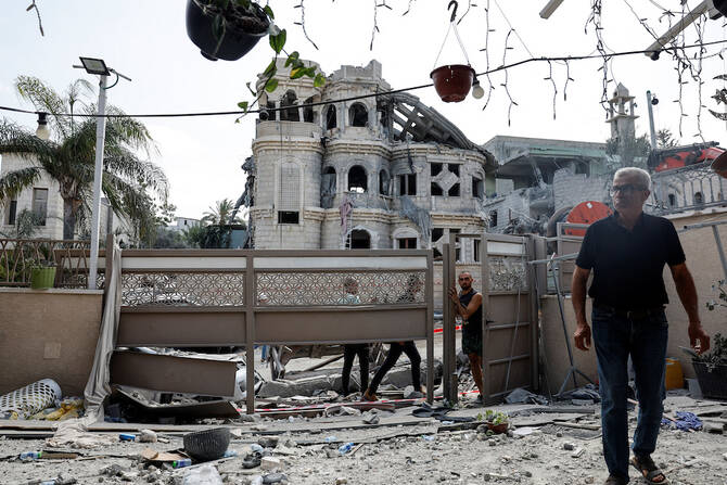 Men walk after missiles fired from Iran impacted on a residential building in northern Israel on June 15, 2025. (Reuters)