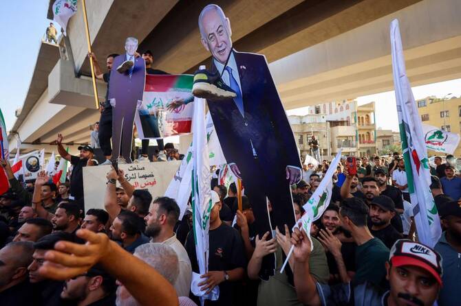 Supporters of Iraqi pro-Iran groups hold a cutout of US President Donald Trump and Israeli Prime Minister Benjamin Netanyahu during a protest in support of Iran, in Baghdad near a bridge leading to the green zone, on Jun. 16, 2025. (AFP)