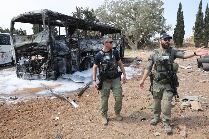 Members of Israeli security forces gesture as they deploy at the impact site of an Iranian missile at a bus depot in Herzliya near Tel Aviv, June 17, 2025. (AFP)