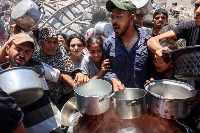 Palestinians try to get food at a charity kitchen providing hot meals in Rimal neighborhood in Gaza City on June 18, 2025. (AFP)