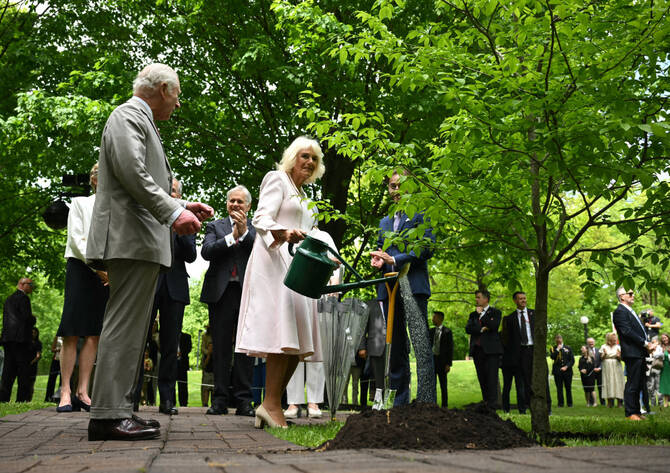 Britain's King Charles III looks on as Queen Camilla waters a tree during a ceremonial tree planting at the official residence of the governor general of Canada, Rideau Hall, in Ottawa, on May 26, 2025. (AFP)