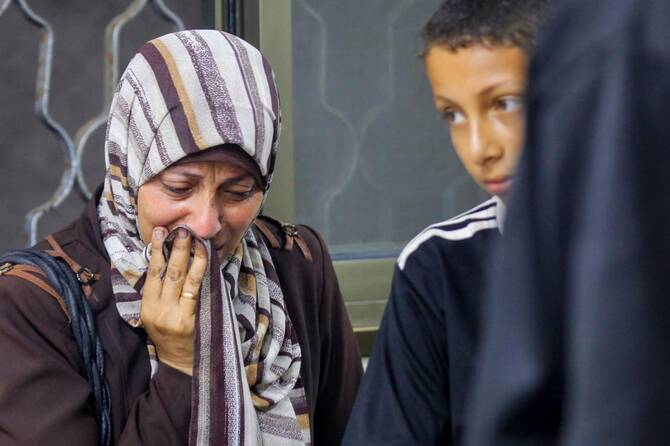 People mourn at the morgue of Al-Awda hospital, in Nuseirat camp in central Gaza on Friday, after more than 25 Palestinians were killed heading to a food distribution center, rescuers said. (AFP)