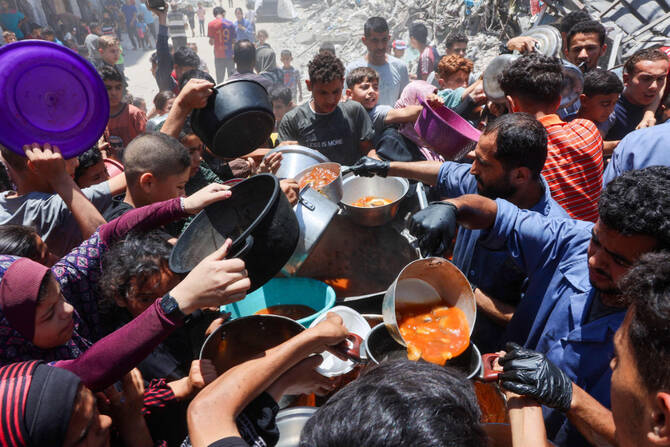Palestinians try to get food at a charity kitchen providing hot meals in Rimal neighborhood in Gaza City on June 18, 2025, amid the ongoing war between Israel and the Palestinian Hamas movement. (AFP)