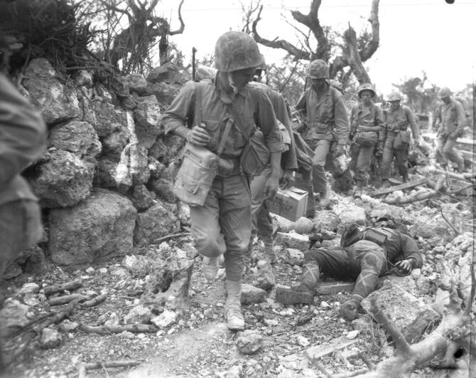 A photo released by US Marines showing a Marine looking back at the body of a dead Japanese soldier while his platoon passes a small village on Okinawa, Japan. (US Marines/AP)
