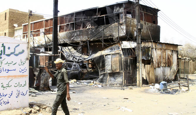 A Sudanese army soldier waves as he walks past a war-damaged building in Salha, south of Omdurman, two days after the Sudanese army recaptured it from the paramilitary Rapid Support Forces (RSF), on May 22, 2025. (AFP/File)
