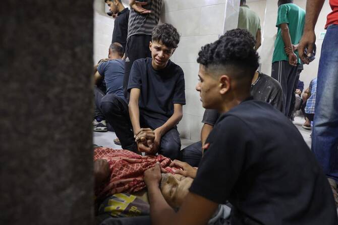 Palestinian youths mourn by the body of a relative killed in Israeli fire at a food aid distribution point set up by the privately-run Gaza Humanitarian Foundation (GHF) on the Salaheddin road, at Al-Awda hospital in the Nuseirat refugee camp in the central Gaza Strip on June 24, 2025. (AFP)