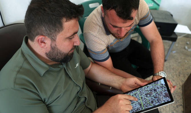 Syrian architect Abdel Aziz al-Mohammed (L) shows on a tablet an interactive map that he created, revealing the detailed conditions of each house in his village Tal Mardikh, in Syria's northwestern Idlib province, on June 2, 2025. (AFP)