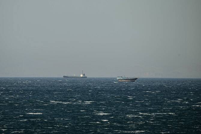 A ship and a Dhow sail in the Strait of Hormuz off the coast of Khasab, Oman. June 24, 2025 (File/AFP)