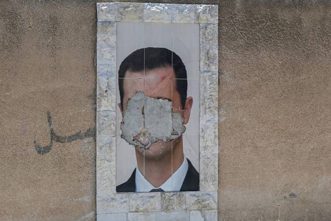 A defaced portrait of Syria's ousted president Bashar al-Assad hangs on a wall in the capital Damascus, June 2, 2025. (AFP)