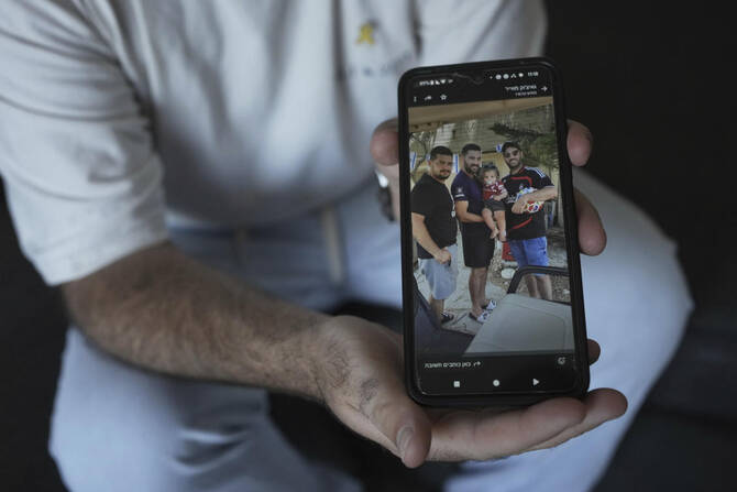 Liran Berman holds a picture on his mobile phone in Or Akiva, Israel, on Jun. 25, 2025, showing himself, right, and brothers, Ziv, left, and Gali, center, who were abducted by Hamas-led militants on Oct. 7, 2023. (AP)