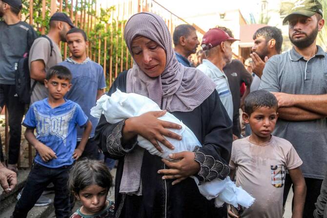 Mother of Yahya Fadi Al-Najjar, an infant who died due to malnourishment, mourns as she holds his body during the funeral at Nasser Medical Complex in Khan Yunis in the southern Gaza Strip on July 20, 2025. (AFP)