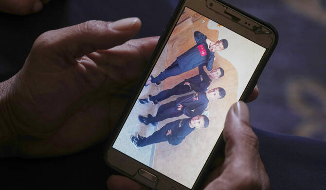 Hatem Al-Nouri shows a photo of his children Amir, 4, right, and Omar, 8, second from right, accompanied by their brothers, as he talks about when the two were killed in an Israeli strike while waiting to receive nutritional supplements at a medical clinic, during an interview at his home in Deir al-Balah, Gaza Strip, Friday, July 11, 2025. (AP)