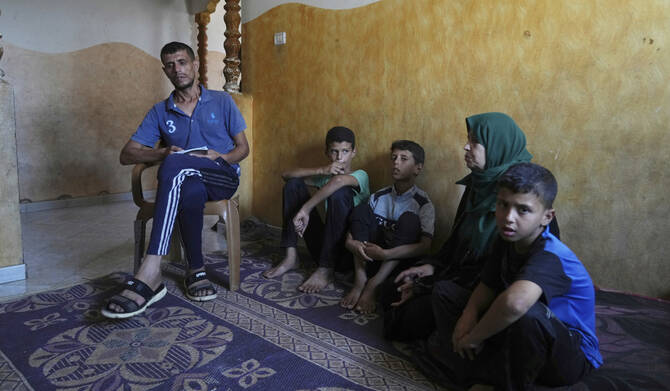 Hatem Al-Nouri, the father of two children who were killed, and one injured, in an Israeli strike while waiting to receive nutritional supplements at a medical clinic, sits with his family during an interview at his home in Deir al-Balah, Gaza Strip, Friday, July 11, 2025. (AP)