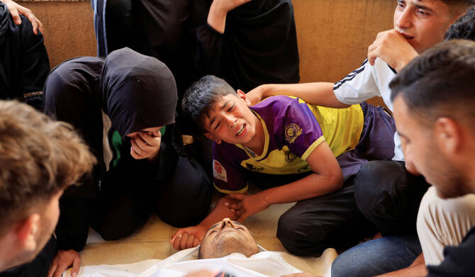 A Palestinian boy reacts alongside his mother as he mourns next to the body of his father, during the funeral of Palestinians killed in morning Israeli strikes on tents sheltering displaced people, according to medics, at Nasser Hospital in Khan Younis, southern Gaza Strip, July 14, 2025. (REUTERS)