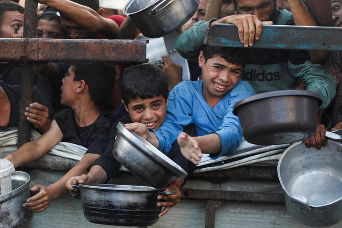 Palestinian children wait to receive food from a charity kitchen, amid a hunger crisis, in Gaza City, July 14, 2025. (Reuters)