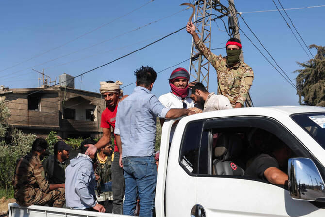Tribal and Bedouin fighters cross the al-Dur village in Syria's southern Sweida governorate as they mobilize amid clashes with Druze gunmen on July 18, 2025. (AFP)