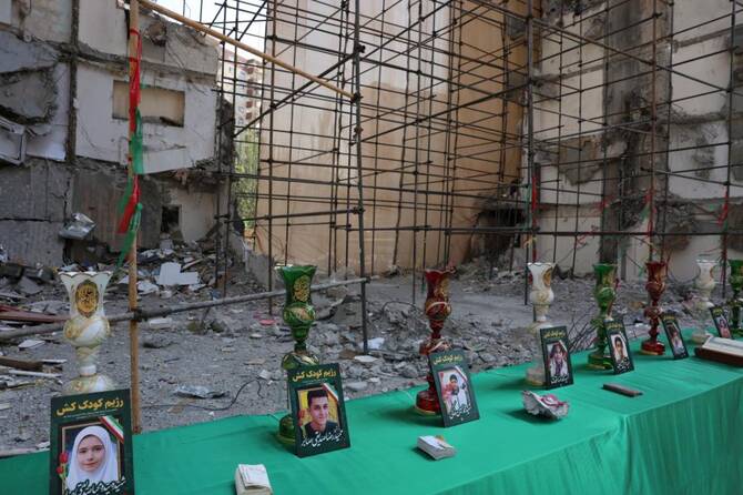 Pictures of children killed in Israeli airstrike a Chamran residential complex, which killed at least 60 people on June 13, are set up in front of the damaged building in Tehran. (File/AFP)